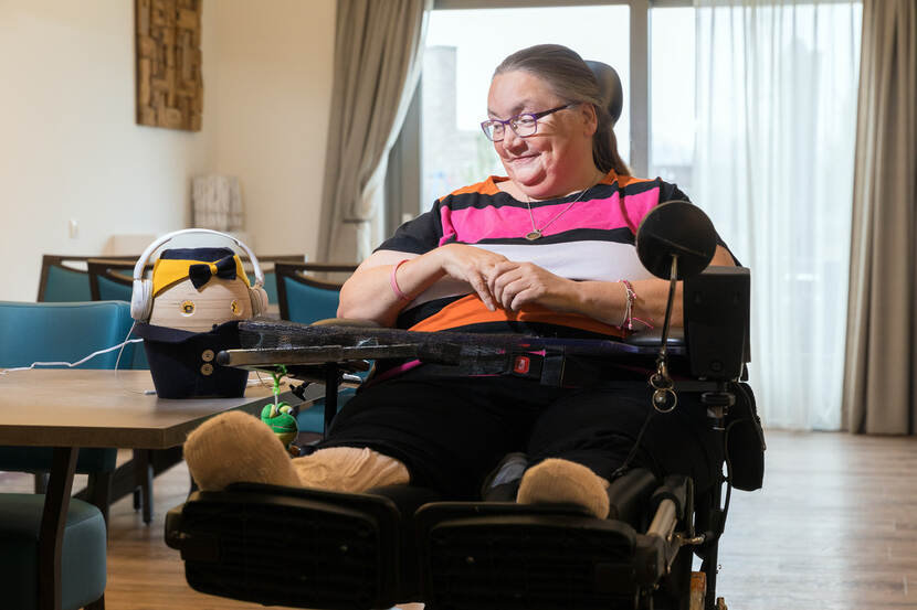 Een vrouw zit in een rolstoel en kijkt naar een robot